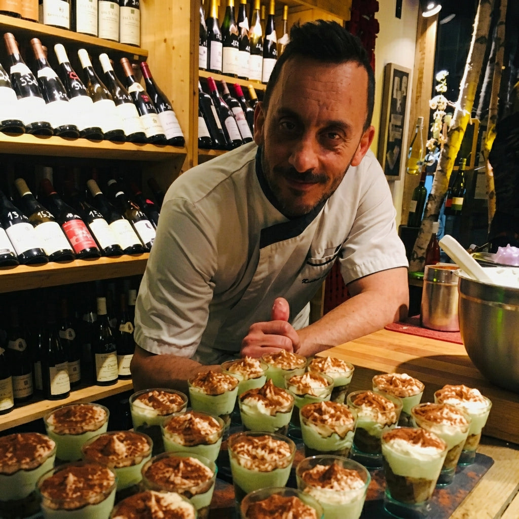 Un cuisinier présente des verrines disposées sur le comptoir devant les étagères de vins.